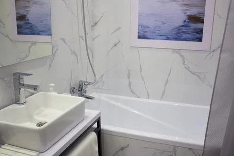 The bathroom has a modern design. In the photo, a sink, a bath, a curtain. Stock Photos