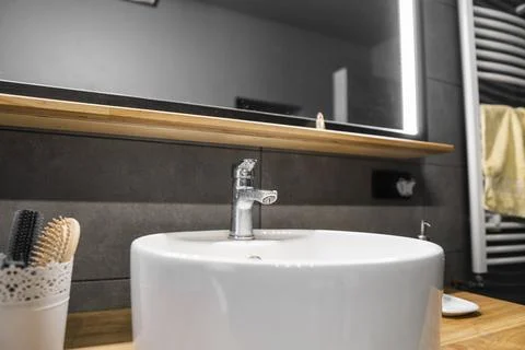 Bathroom interior with grey tile on a wall, stylish round sink and tap on a oak Stock Photos