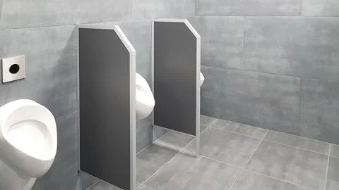 The bathroom interior is lined with white ceramic tiles. Oval ceramic urina.. Stock Photos