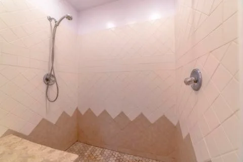 Bathroom interior with shower installed on the wall with white and brown tiles Stock Photos