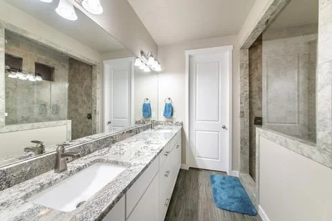 Bathroom with long vanity with two sinks and walk-in shower with half wall and Stock Photos