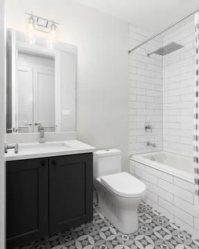 A bathroom with a pattern tile flooring and subway tile shower. Stock Photos