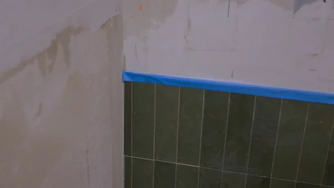 Bathroom renovation in progress with partially tiled wall and exposed plaster Stock Footage 332185776