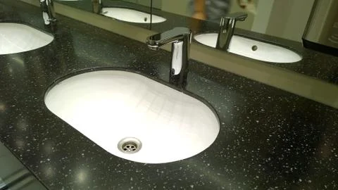 Bathroom sinks and touchless taps in public toilet and restroom. Modern faucet. Stock Photos