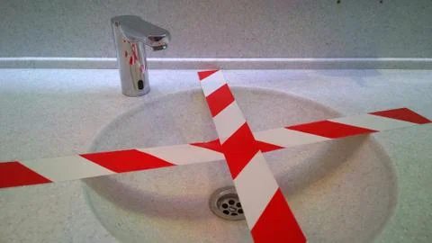 Bathroom sinks and touchless taps with red barrier tape for social distance Foto stock