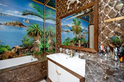A bathroom with a tropical theme, featuring a large bathtub and a mirror Stock Photos