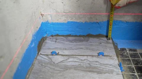 Bathroom under construction with worker measuring new floor tiles with laser Stockfoto's
