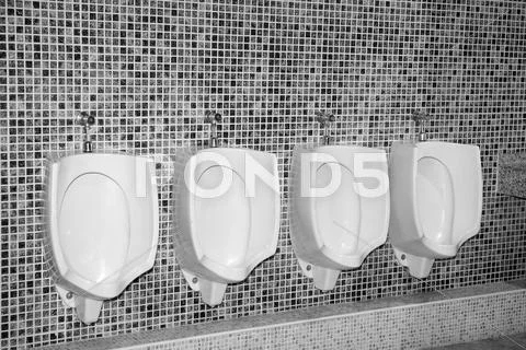 Bathroom urinal in a row with gray tiles Stock Photos