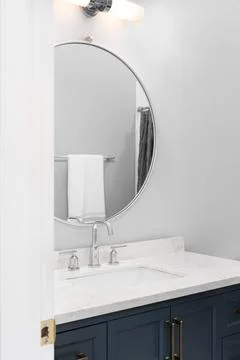 A bathroom's blue cabinet and circular mirror. Stock Photos