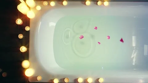 Bathtub is filled with clear clean blue water pink petals of fresh flowers Stock Footage 310329793