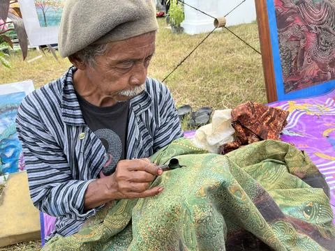 Batik drawing process by an old man on a fabric. Stock Photos