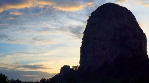 Bats fly out of the cave in the mountains at sunset. Stock Footage 112994275