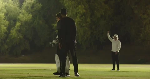 Batsman under floodlights hesitating after wicketkeeper underarming ball to Stock Footage 344253112