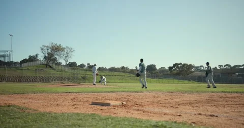 Batter hitting grounder forcing runner diving into first, male fielders making Stock Footage 338434064