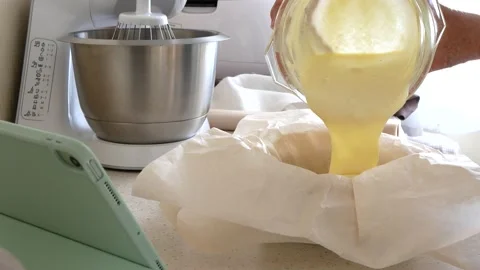 Batter is poured into round cake mold covered with baking paper Stock Footage 225740600