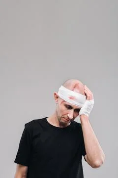 A battered and battered man in a black T-shirt stands against a gray backgrou Fotos Stock