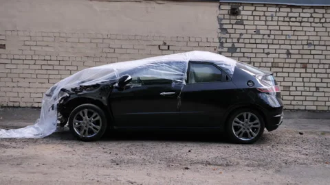 Battered car is parked in front of the garages. black battered car is covered Stock Footage 244975833