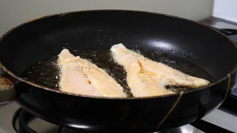 Battered fish fillets frying in hot oil on a pan Stock Footage 99163329