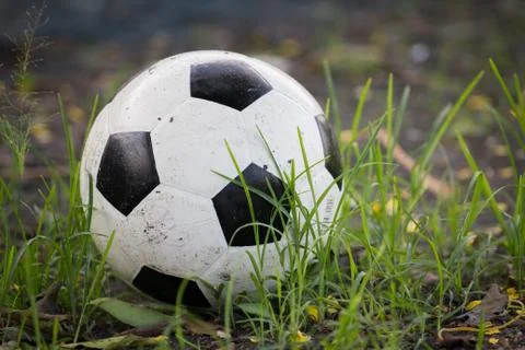 Battered old soccer ball, slightly deflated, in long grass of unmowed footbal Stock Photos
