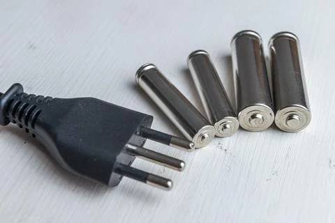 Batteries on a light surface, with the plug next to it.  Stock Photos