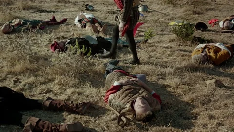 Battle aftermath in a dry field with fallen soldiers and a warrior Stock Footage 327944616