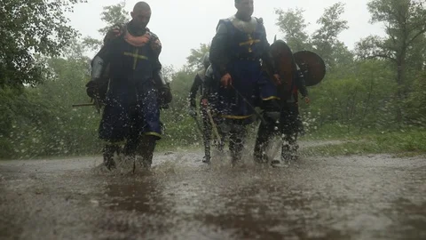 Battle squad of medieval knights goes through a puddle on road in rain. Stock Footage 109490219