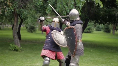 Battle of two medieval warriors in full sets of armor with swords and shields. Stock Footage