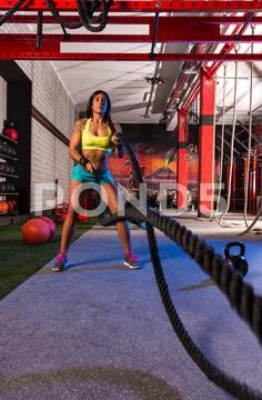 Battling ropes girl at gym workout exercise Stock Photos