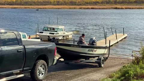 BAUDETTE, MN - 29 OCT 2025: Pickup backing fishing boat down ramp Stock Footage 322720564