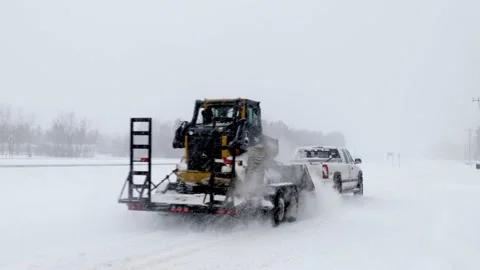 BAXTER, MN - 22 FEB 2022: Pickup, trailer, and Deere Track Loader in winter Stock Footage 171936076