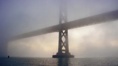 Bay Bridge support and tower is surrounded by fog and gorgeous sunrise glow 스톡 동영상 242830941