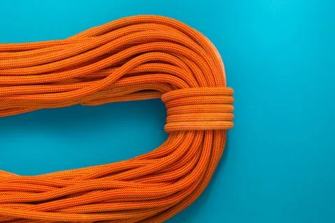 Bayed rope for climbing on a blue background. Orange rope for mountaineering  Stock Photos