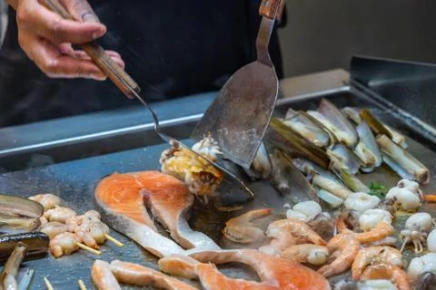 BBQ chef using spatula while frying seafood in buffet restaurant Stock Photos
