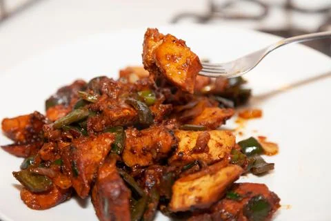 BBQ chicken on a fork above chicken cubes with chopped poblano, green peppers, a Foto stock