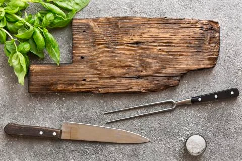 BBQ concept old board on concrete. Green basil leaves, meat knife and barbecue 写真素材