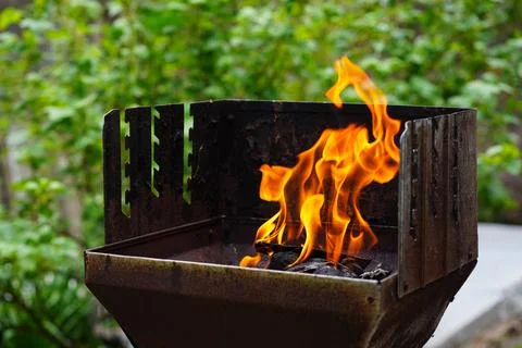 BBQ grill flame burning fire, barbecue outdoors for cooking food in garden. Stock Photos