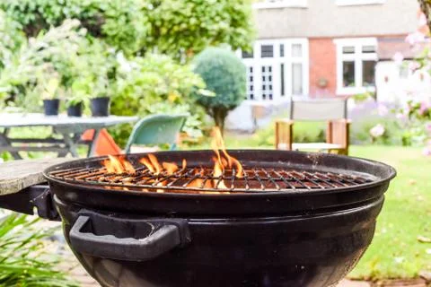 Bbq grill with flames in an empty back garden preparing to cook outside Stock Photos