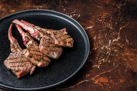 BBQ Grilled lamb chops steaks in a plate. Dark background. Top view. Copy space Stock Photos