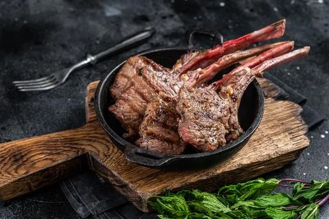 BBq Grilled lamb mutton chops steaks in a pan. Black background. Top view Stock Photos