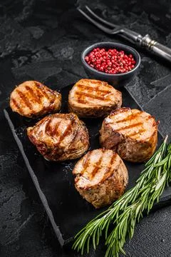BBQ grilled pork medallions steaks, tenderloin fillet meat. Black background Stock Photos