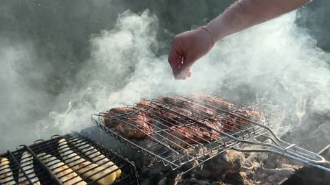 Bbq meat on a grill grate. Man sprinkles salt on meat. Stock Footage 210774382