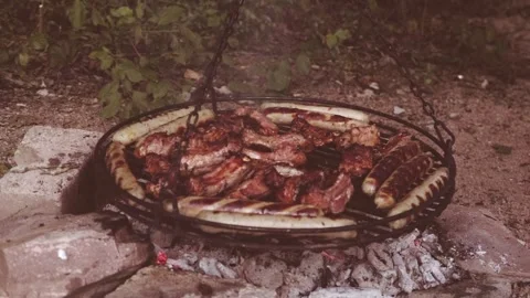 BBQ Pork ribs, meat, and sausages grilling over open fire, barbecue camping.. Stock Footage 335390883