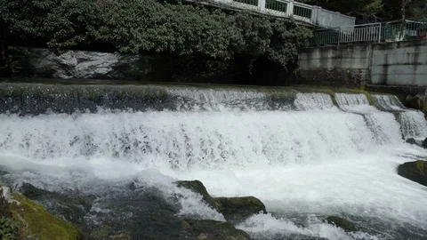 Bbridge over fast mountain river river with waterfall. View of a fast moving Stock-Footage 114878458