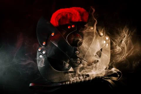 BDSM mask resting on a dark surface with subtle hints of smoke Stock Photos
