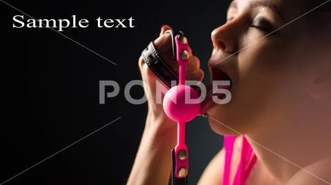 BDSM outfit for adult sex games. A young woman licks pink gag ball Stock Photos