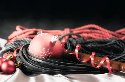 Bdsm still life leather whip and christmas balls on silver fabric close up Stock Photos