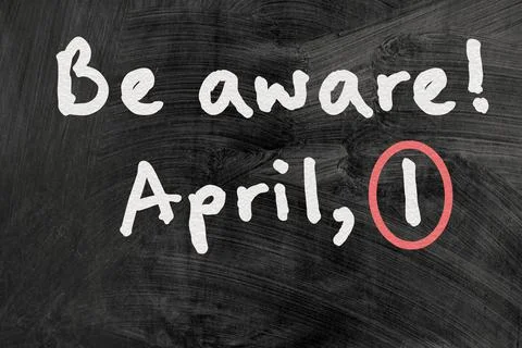 Be aware on blackboard note over a dark background. april fools day Stock Photos