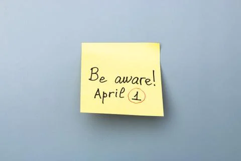 Be aware on yellow sticky note over a grey background. april fools day Stock Photos