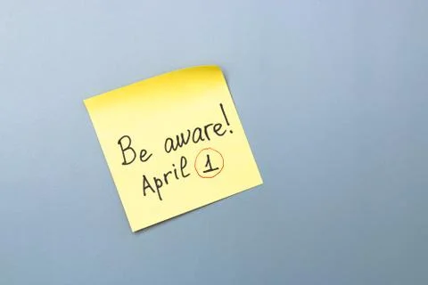 Be aware on yellow sticky note over a grey background. april fools day Stock Photos