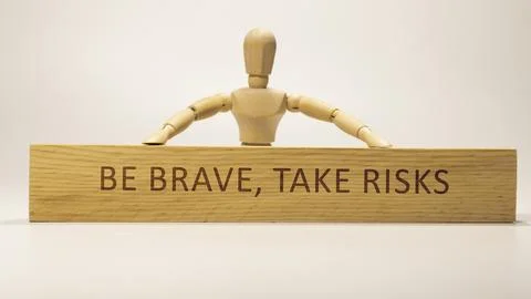 Be brave, take risks written on wooden surface. Motivation and personal devel Stock Photos